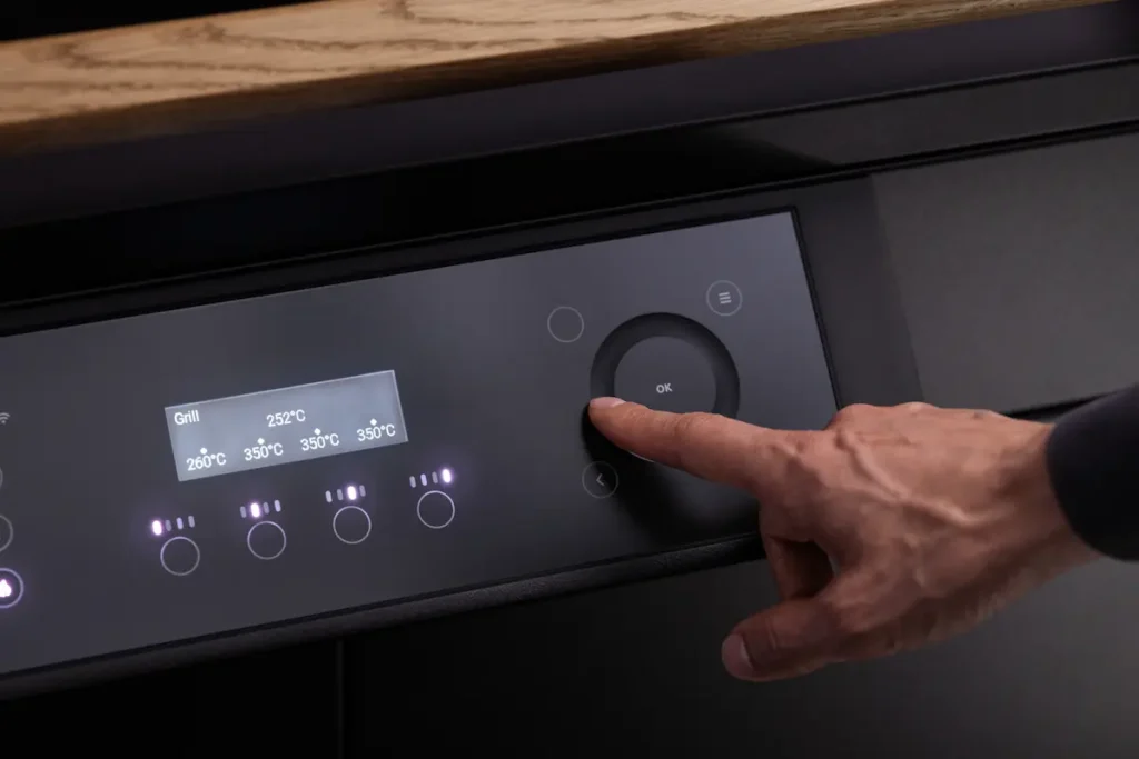 Hand bedient das Touch-Display des KOQOON GQ4 zur Einstellung von Grilltemperaturen.