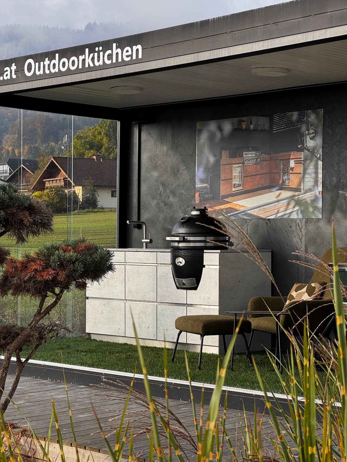 Blick von außen in den Schauraum: Outdoorküche mit MONOLITH Kamado-Grill und Küchenblock.