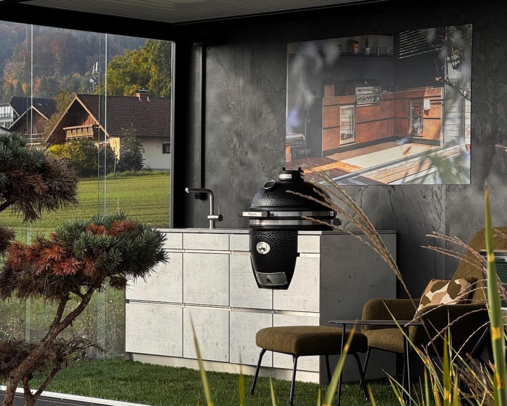 Blick von außen in den Schauraum: Outdoorküche mit MONOLITH Kamado-Grill und Küchenblock.